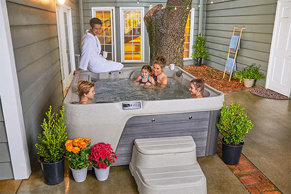 Family relaxing together in a mid size hot tub on a backyard patio