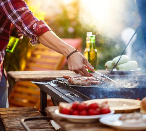 Young handsome men roasting barbecue on grill in cottage countryside. Copy space.